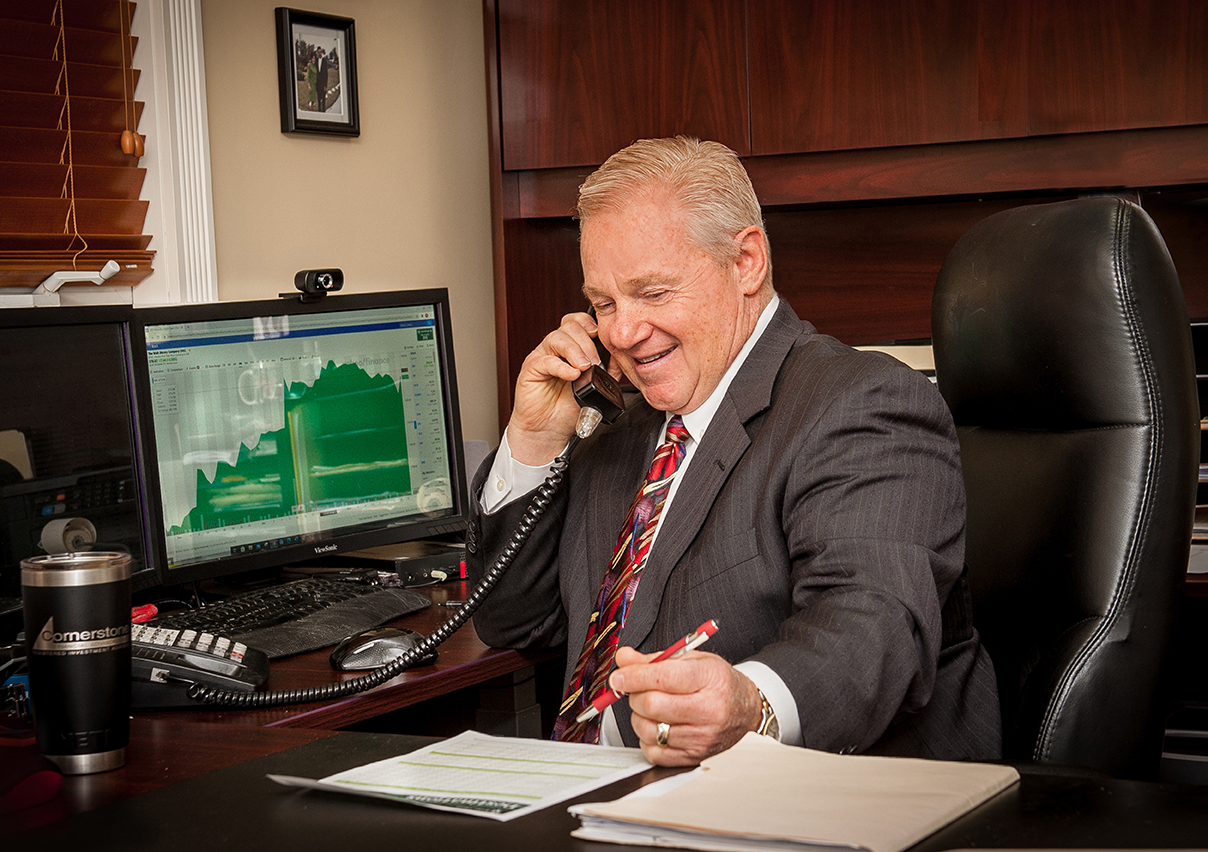 A man sitting at a desk, engaged in a phone conversation.